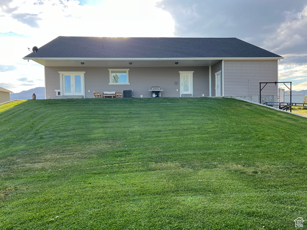 Rear view of property featuring central air condition unit, a yard, and french doors