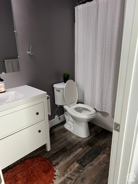 Full bathroom featuring shower / bath combination with curtain, vanity, toilet, and hardwood / wood-style flooring