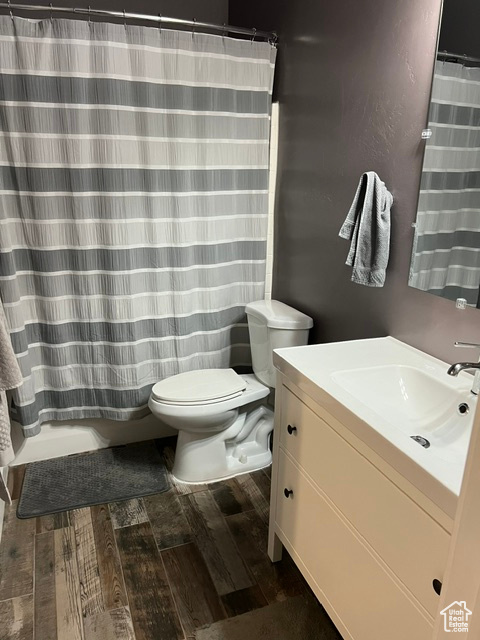 Bathroom featuring hardwood / wood-style floors, toilet, a shower with shower curtain, and vanity
