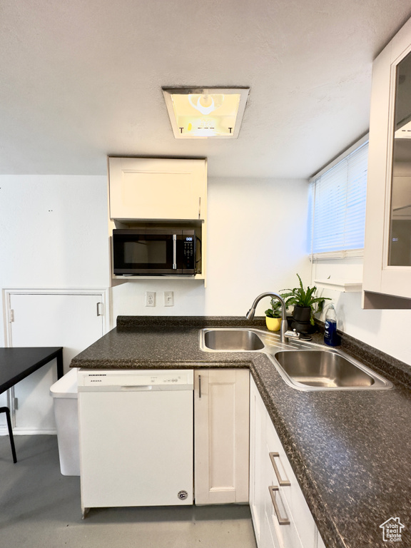 Kitchen with white cabinets, dishwasher, and sink