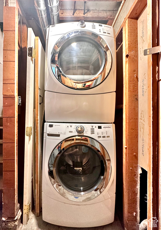 Clothes washing area featuring stacked washer and clothes dryer