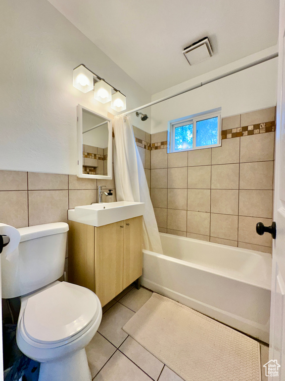 Full bathroom with shower / bath combo, vanity, tile patterned floors, toilet, and tile walls