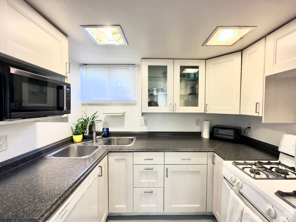 Kitchen featuring white cabinetry, sink, and white appliances