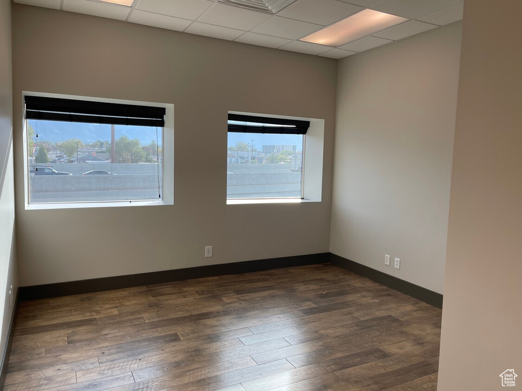 Empty room featuring a drop ceiling and dark wood-type flooring