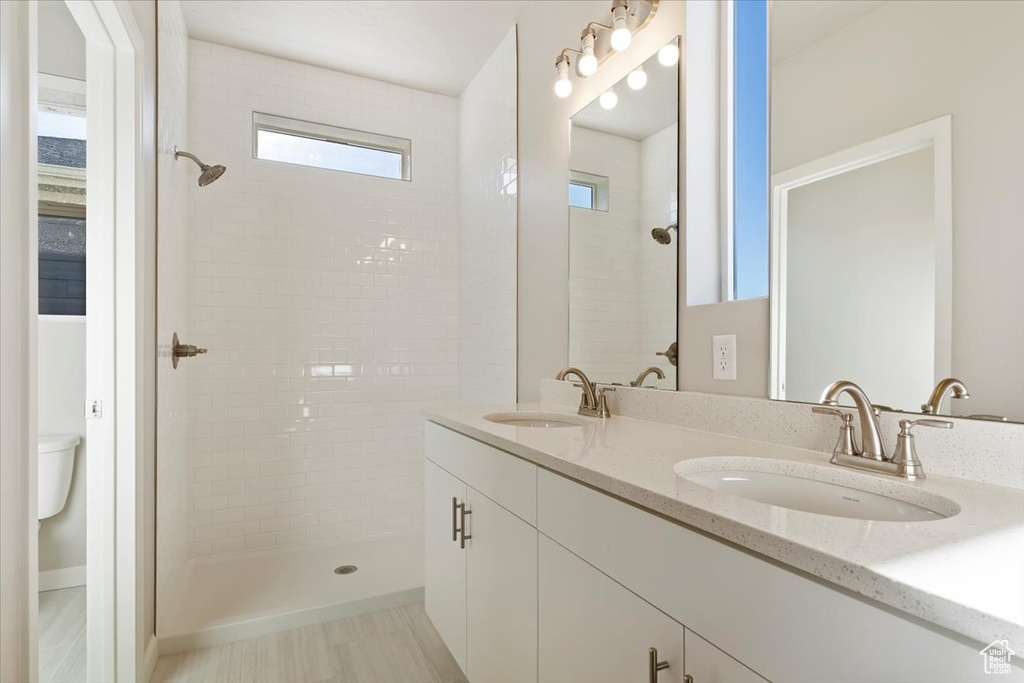 Full bath featuring double vanity, a sink, and a tile shower