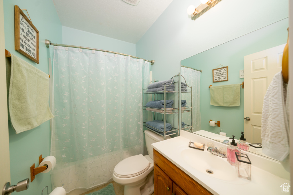 Full bathroom featuring vanity, shower / bath combo, and toilet