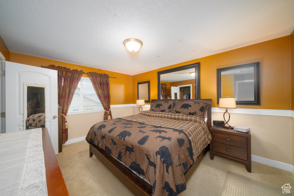 Bedroom featuring light colored carpet and a textured ceiling