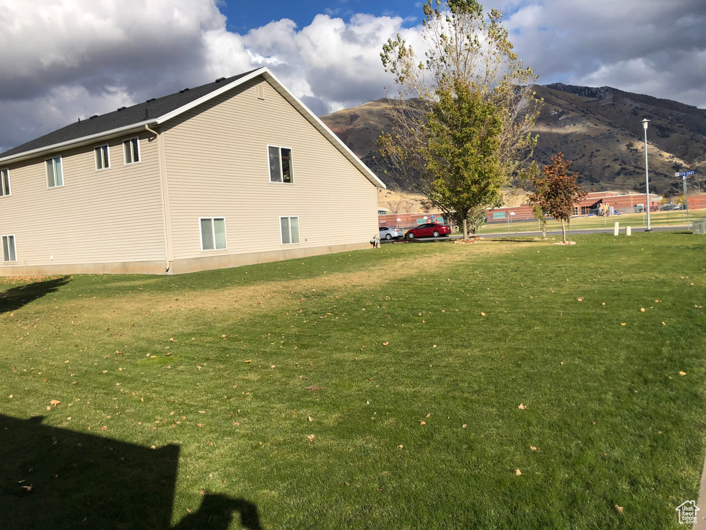 View of side of home featuring a mountain view and a yard