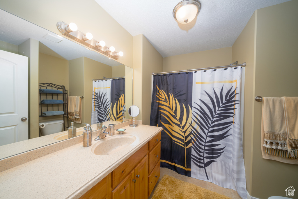 Bathroom with vanity, a shower with shower curtain, a textured ceiling, and toilet