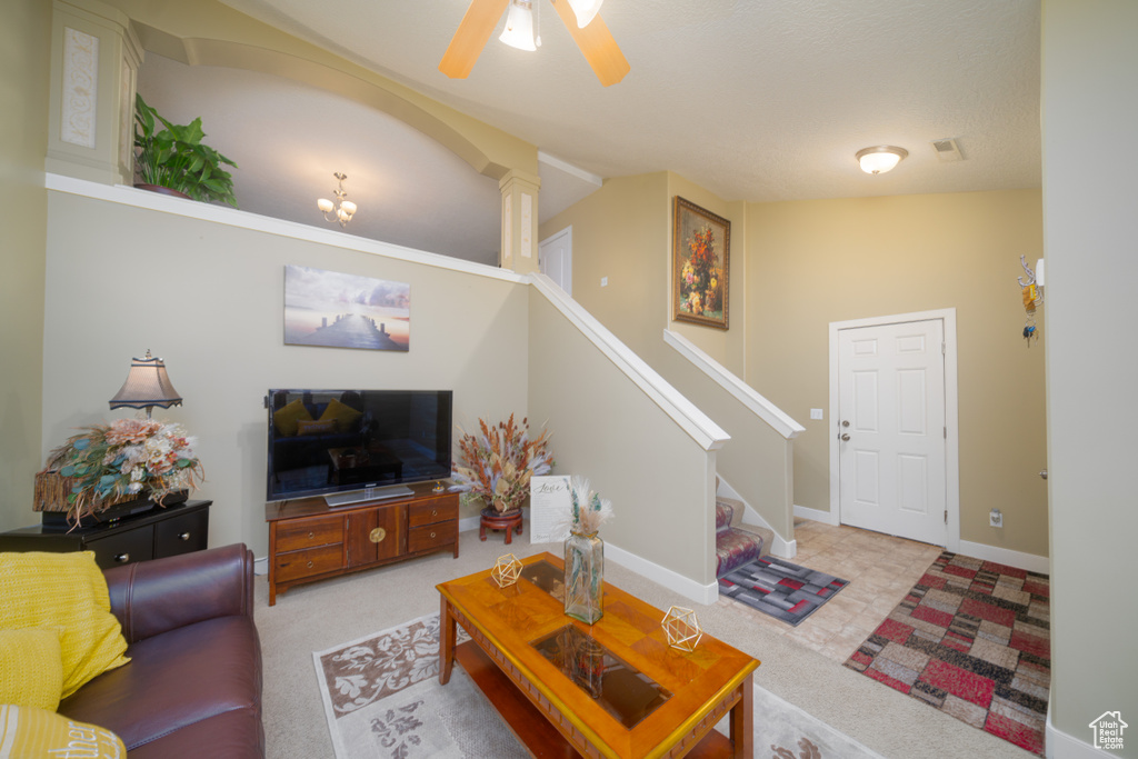 Living room featuring ceiling fan, light colored carpet, and lofted ceiling