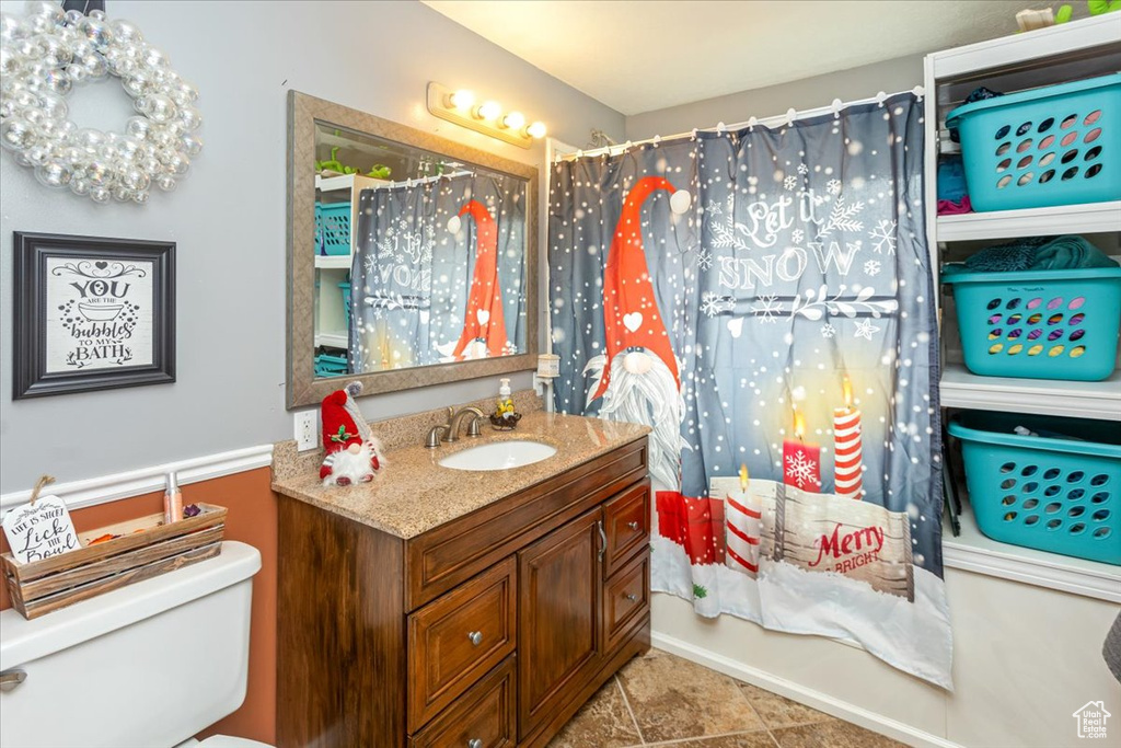 Full bathroom with tile patterned floors, shower / bath combination with curtain, toilet, and vanity