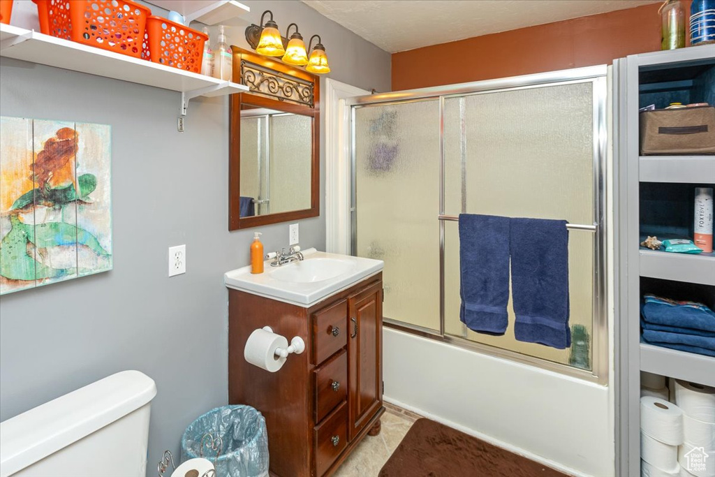 Full bathroom with shower / bath combination with glass door, vanity, and toilet