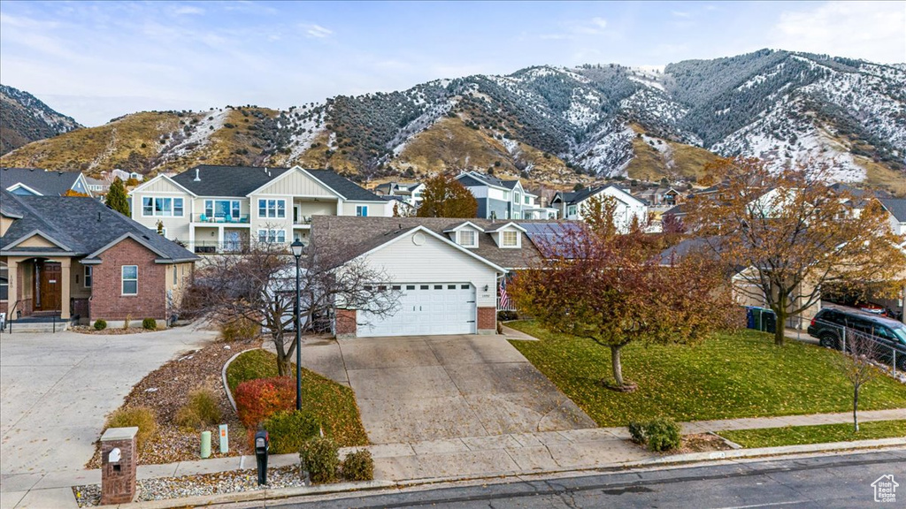 View of front of house featuring a mountain view, a garage, and a front yard