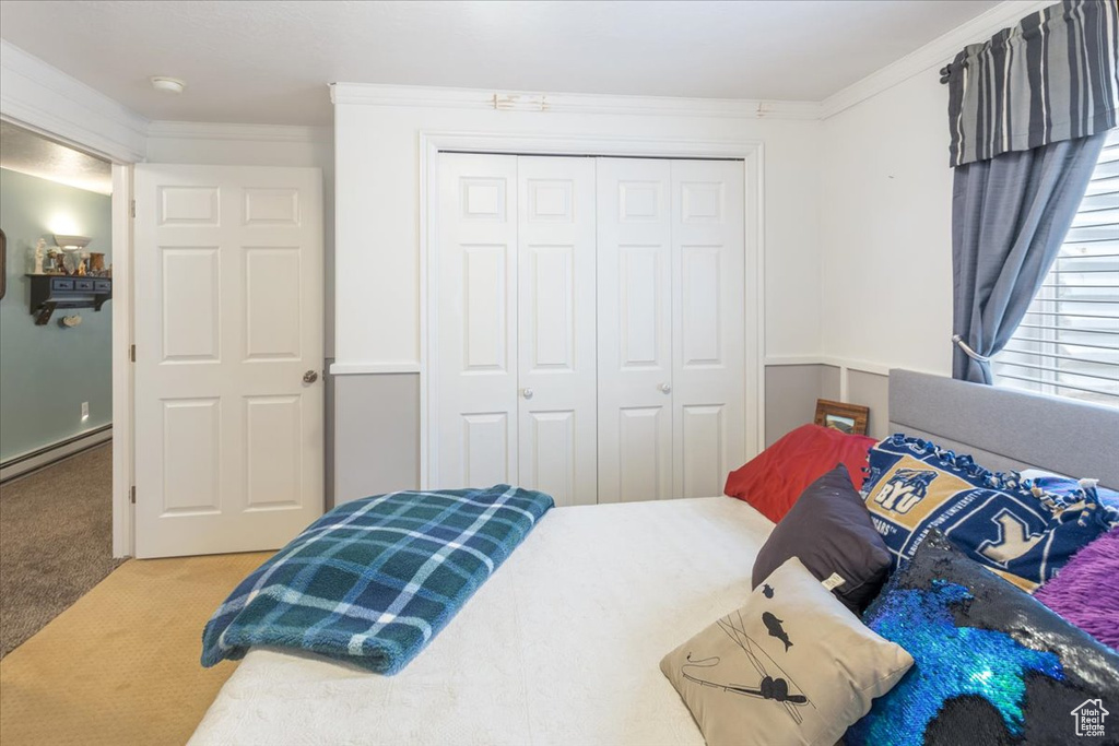 Bedroom with carpet flooring, ornamental molding, baseboard heating, and a closet