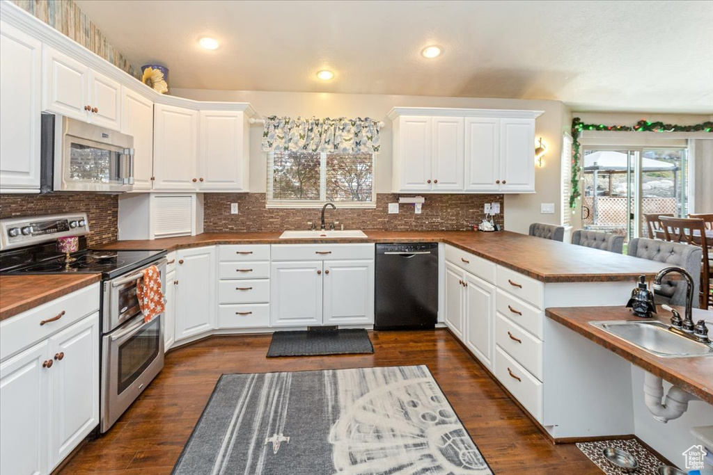 Kitchen featuring white cabinets, stainless steel appliances, dark wood-type flooring, and sink