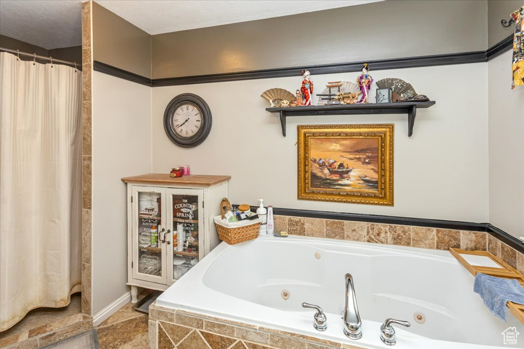 Bathroom featuring a textured ceiling and a relaxing tiled tub