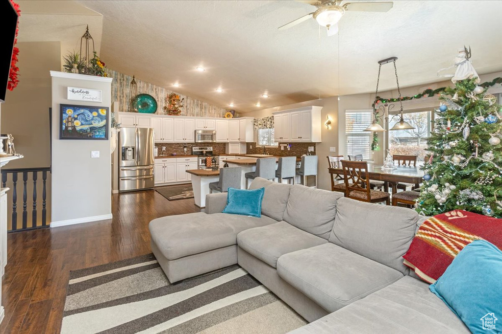 Living room with ceiling fan, dark hardwood / wood-style flooring, and vaulted ceiling