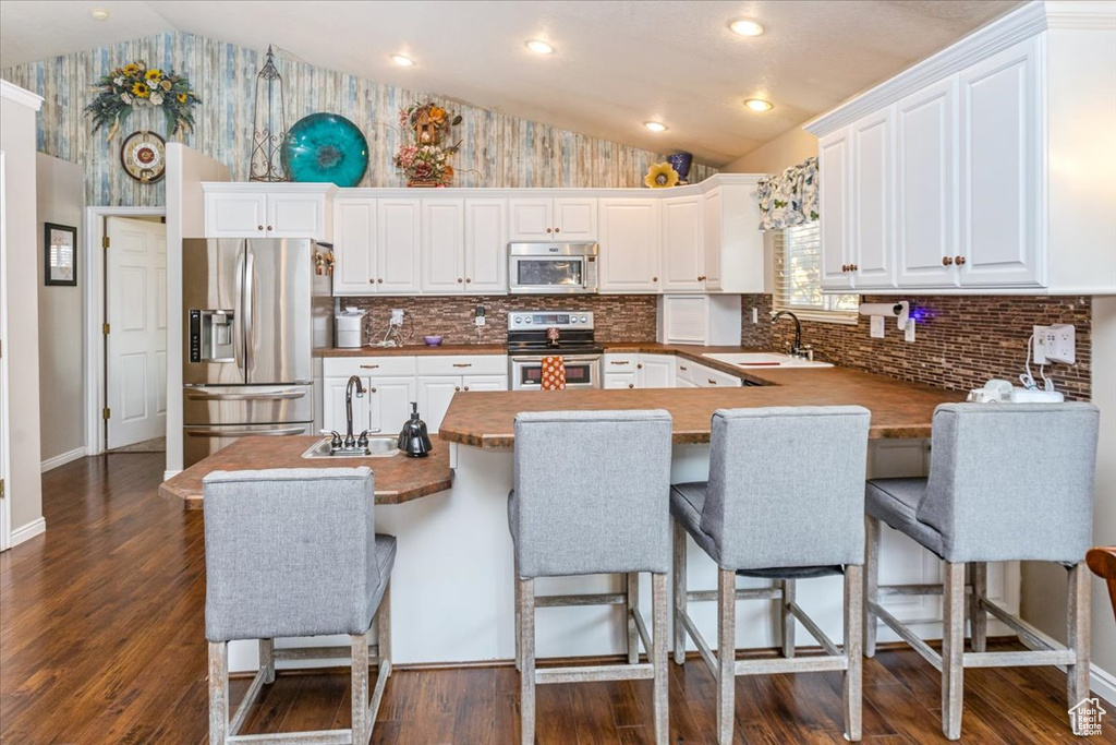 Kitchen featuring white cabinets, lofted ceiling, and stainless steel appliances