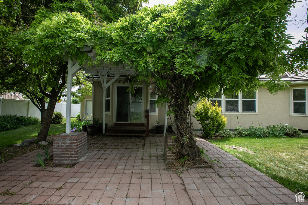 View of exterior entry featuring stucco siding and a patio area
