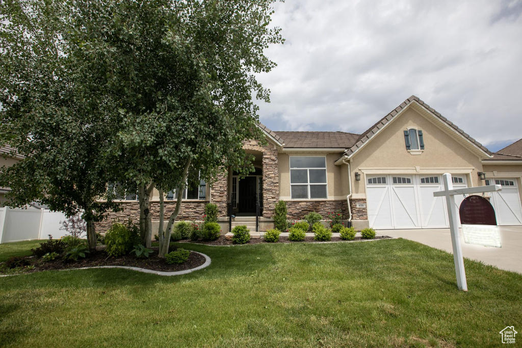 View of front of home featuring stone siding, concrete driveway, stucco siding, and a garage
