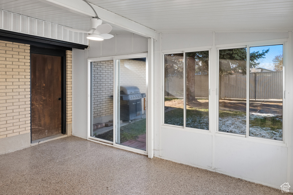 Unfurnished sunroom featuring vaulted ceiling with beams