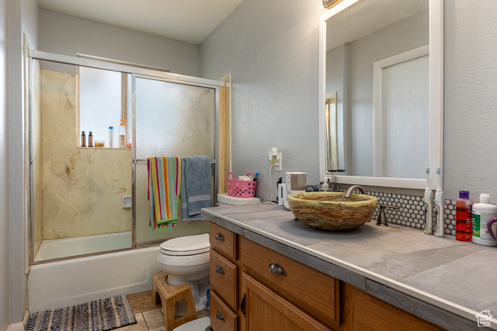 Full bathroom featuring tile patterned flooring, vanity, combined bath / shower with glass door, and toilet