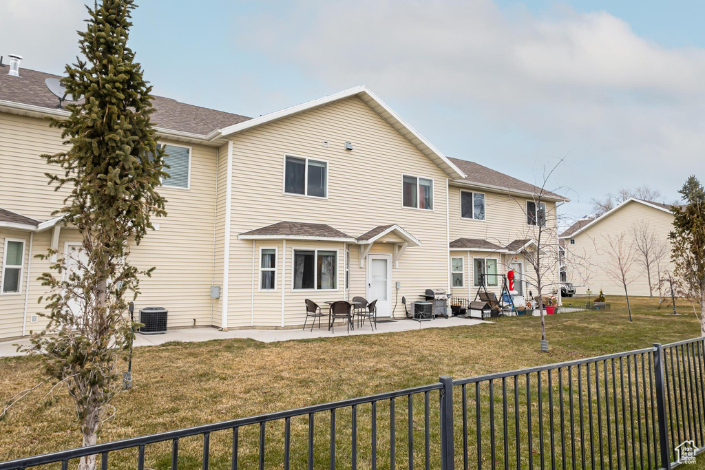 Back of house with a patio, a lawn, and central air condition unit