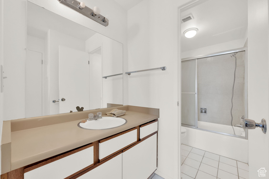 Full bathroom with tile patterned flooring, vanity, toilet, and enclosed tub / shower combo