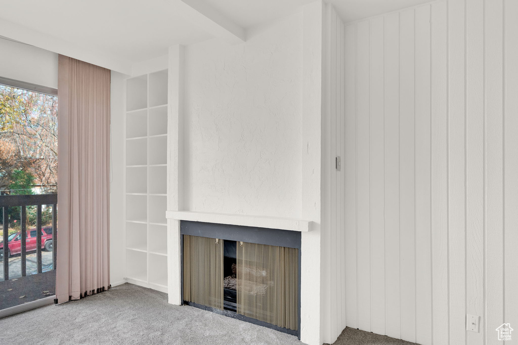 Unfurnished living room with beam ceiling and carpet floors