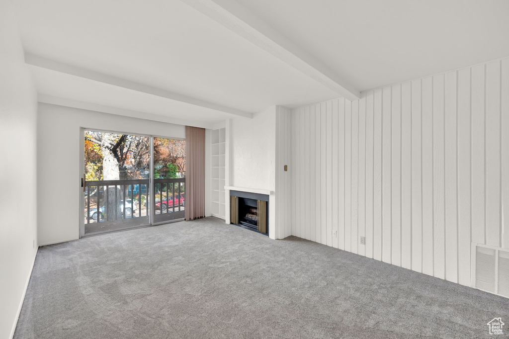 Unfurnished living room with carpet and beam ceiling