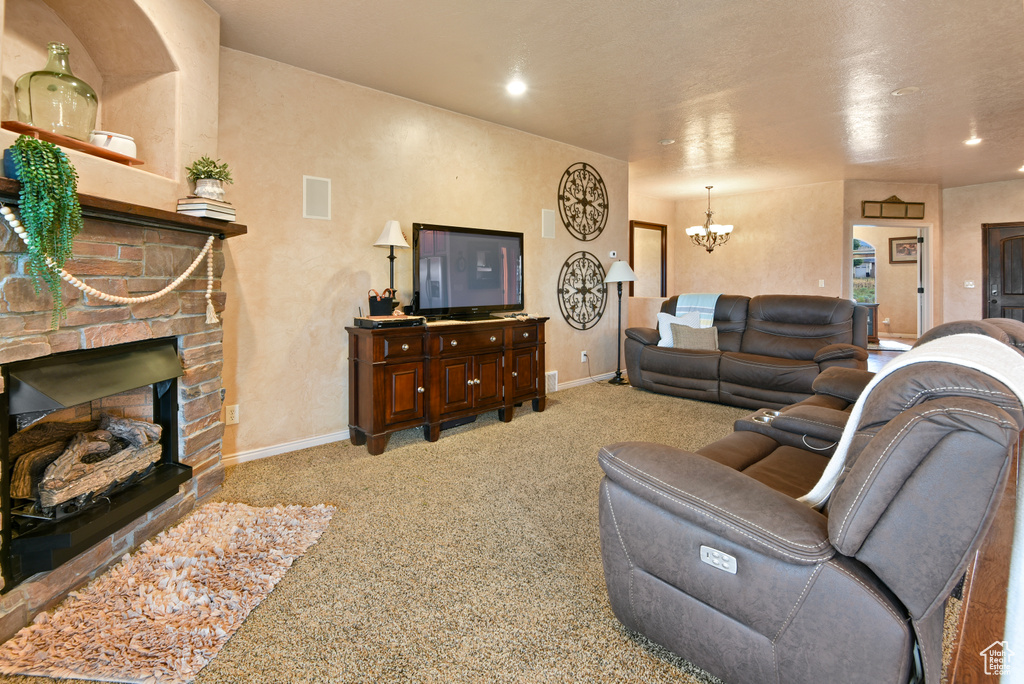Carpeted living room featuring a fireplace and a notable chandelier