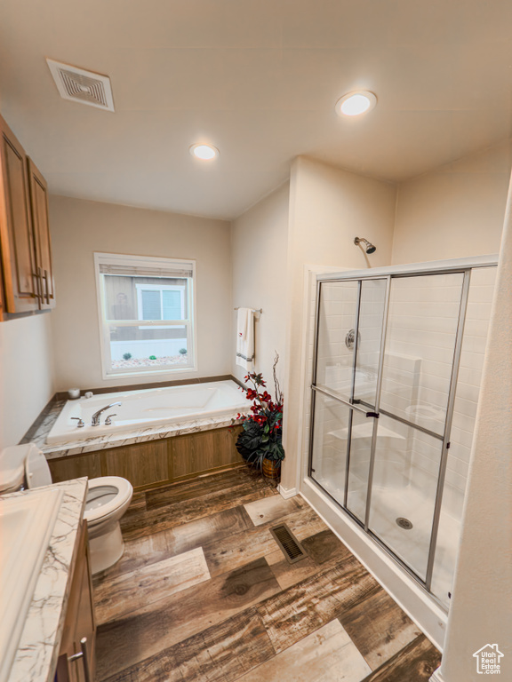 Full bathroom featuring hardwood / wood-style flooring, toilet, and independent shower and bath