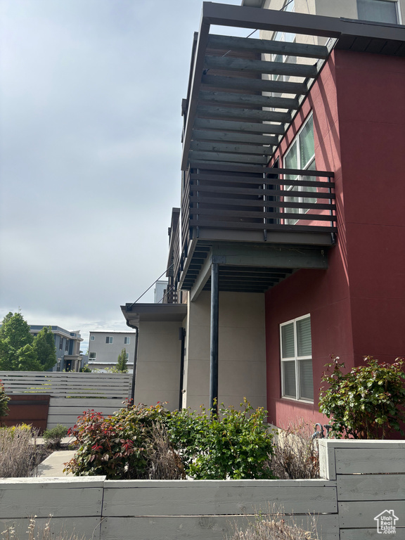 View of side of home featuring fence and a balcony