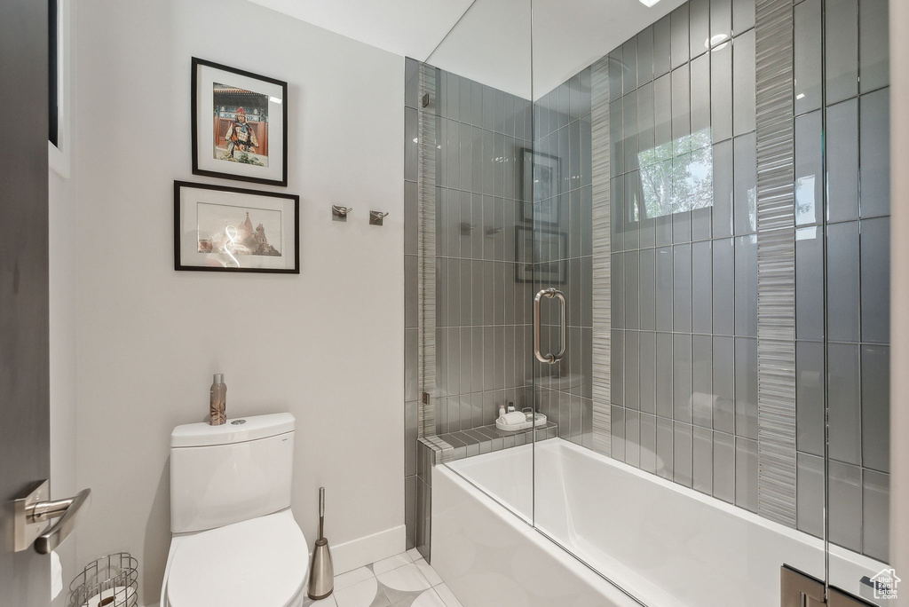 Full bathroom with toilet, baseboards, and shower / washtub combination