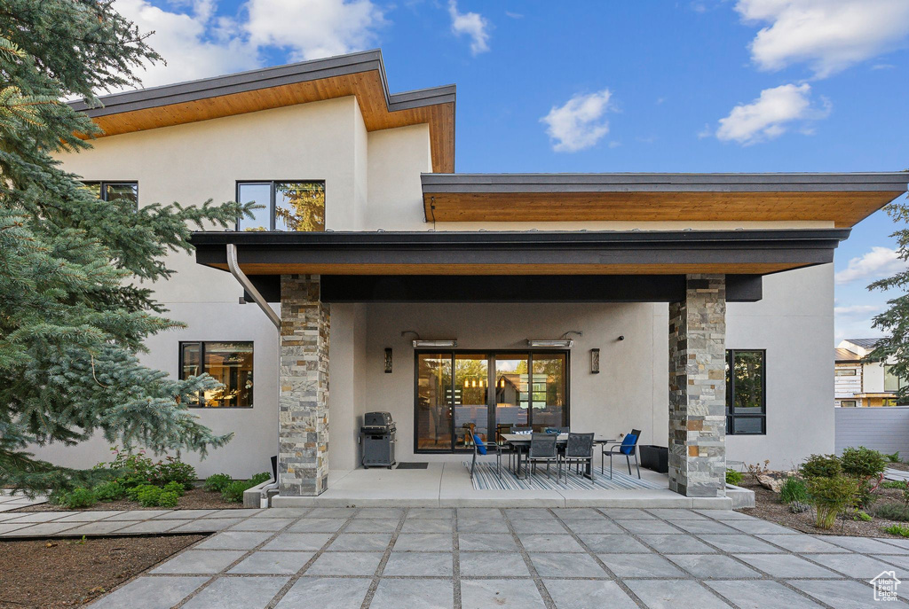 Back of property with stone siding, a patio area, stucco siding, and outdoor dining space