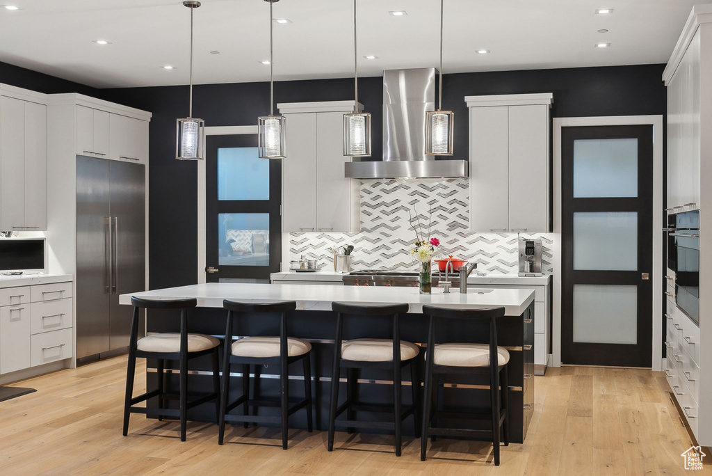 Kitchen with stainless steel appliances, extractor fan, light countertops, decorative backsplash, and recessed lighting