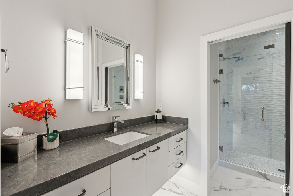 Bathroom featuring marble look tile flooring, a shower stall, vanity, and baseboards