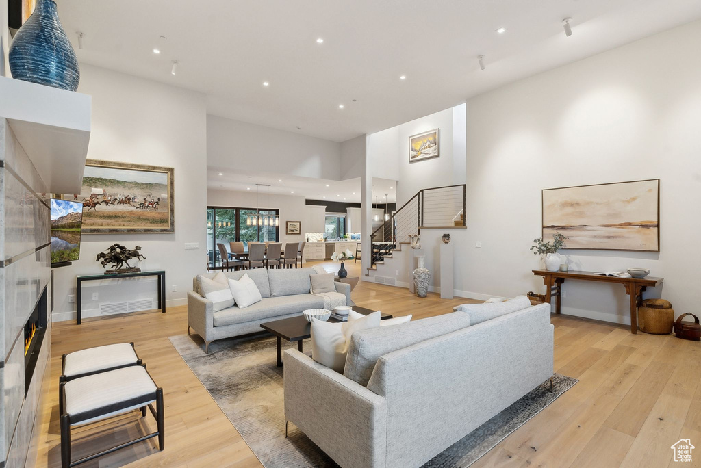 Living area featuring stairway, light wood finished floors, recessed lighting, a high ceiling, and baseboards