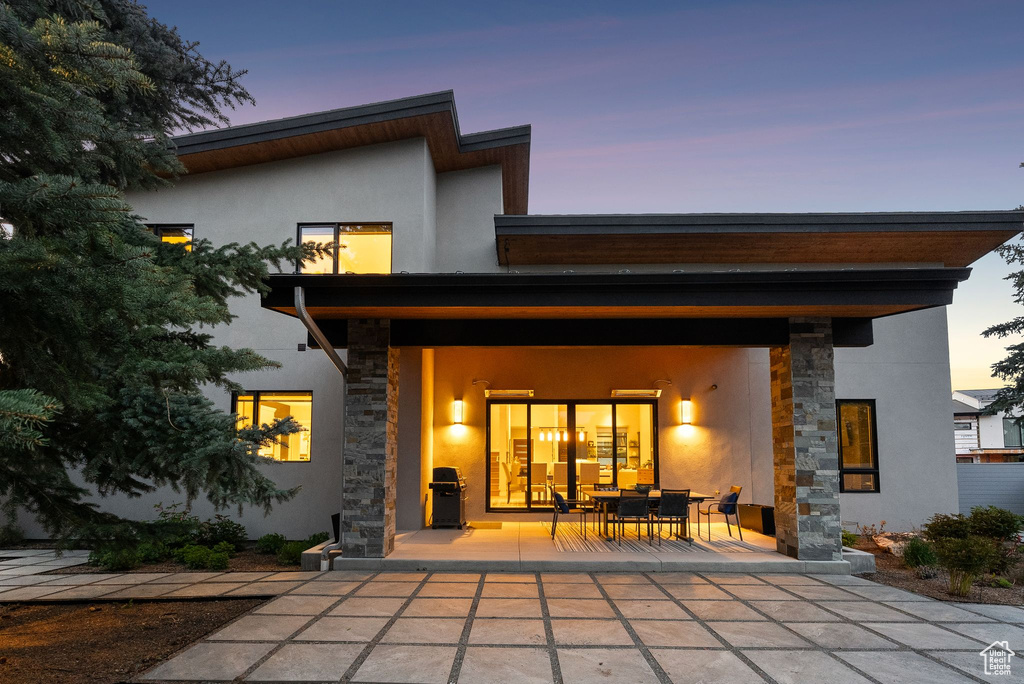 Back of property with stone siding, stucco siding, and outdoor dining area