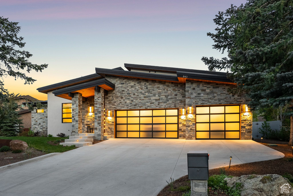 Modern home featuring stone siding, concrete driveway, and a garage