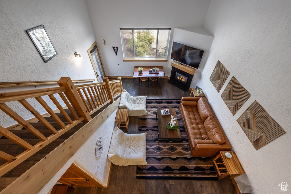 Living room with a glass covered fireplace, wood finished floors, a textured wall, a skylight, and baseboards