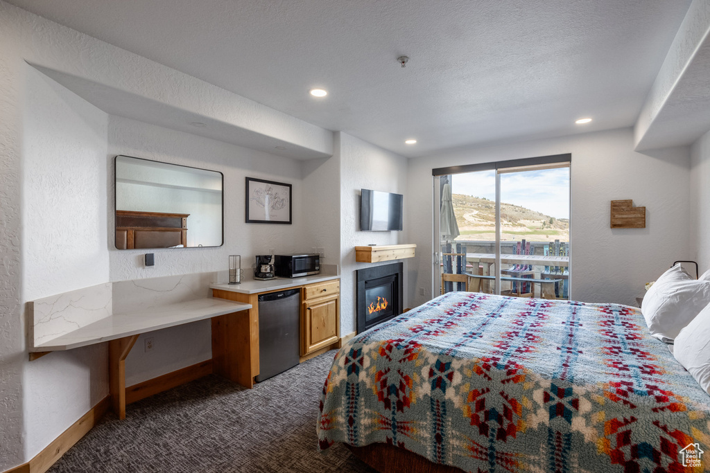 Carpeted bedroom with refrigerator, recessed lighting, baseboards, and a glass covered fireplace