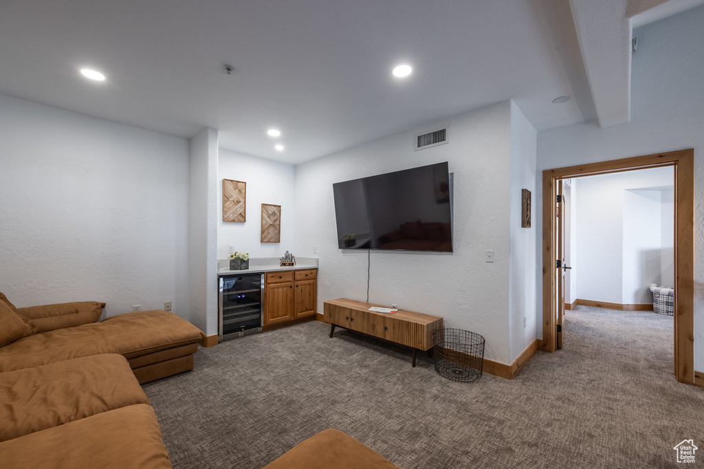 Living room with wine cooler, dark colored carpet, baseboards, recessed lighting, and bar