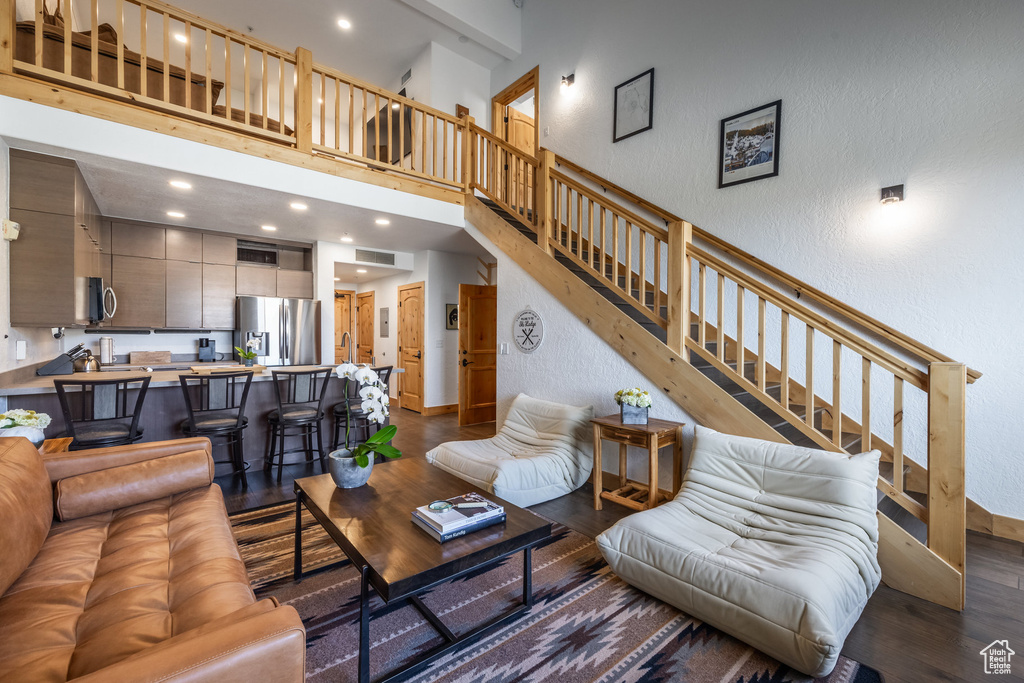Living area with dark wood-style floors, stairway, baseboards, a textured wall, and a towering ceiling