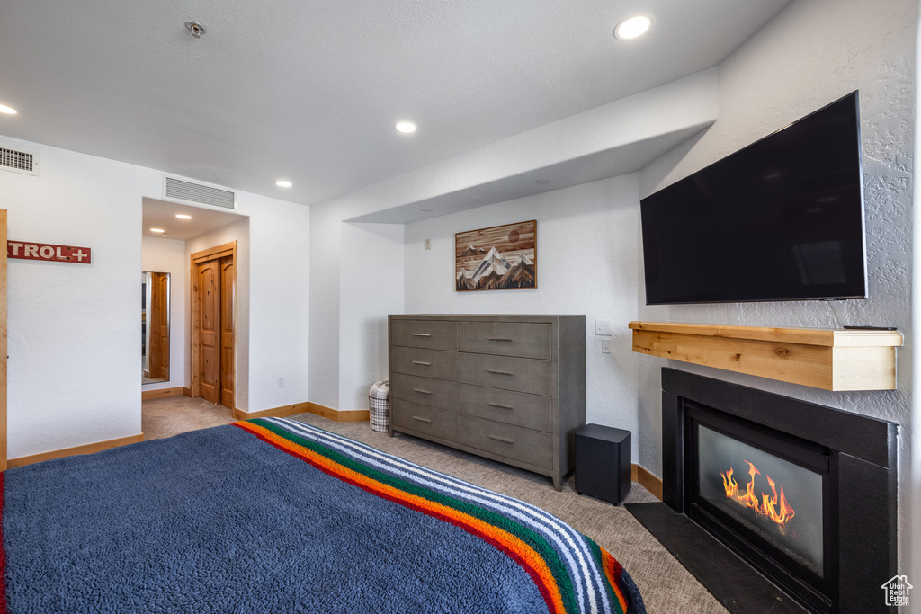 Bedroom with carpet floors, a fireplace with flush hearth, baseboards, and recessed lighting