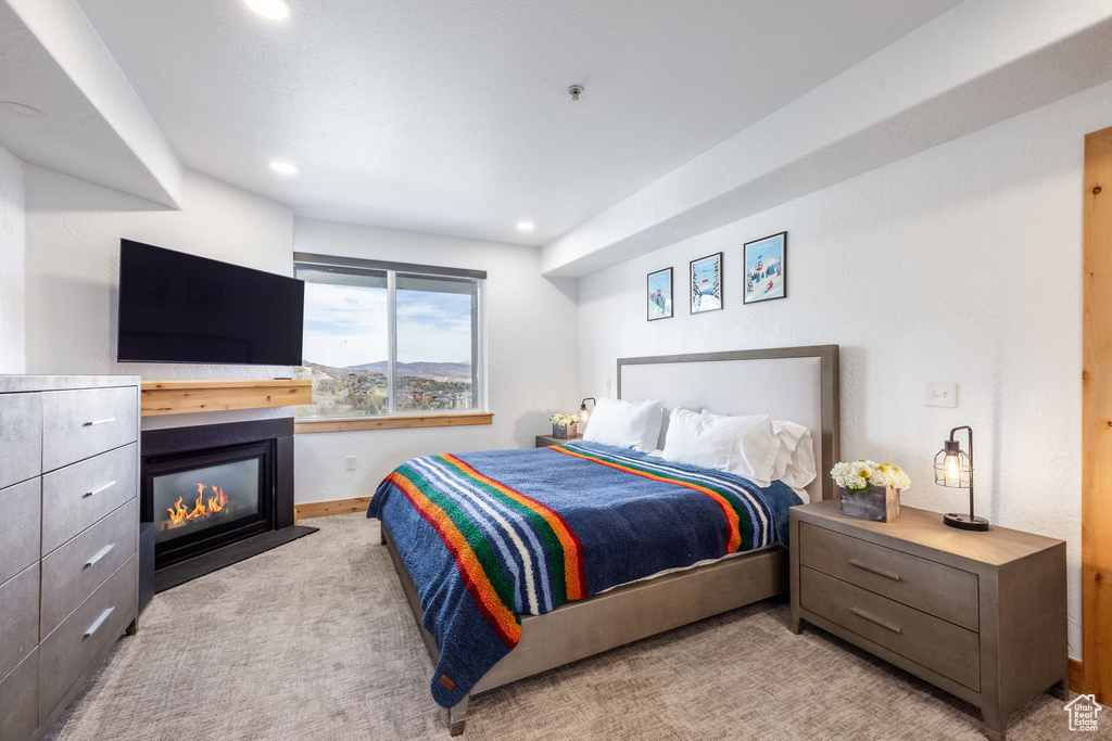 Bedroom featuring light carpet, baseboards, recessed lighting, and a fireplace with flush hearth