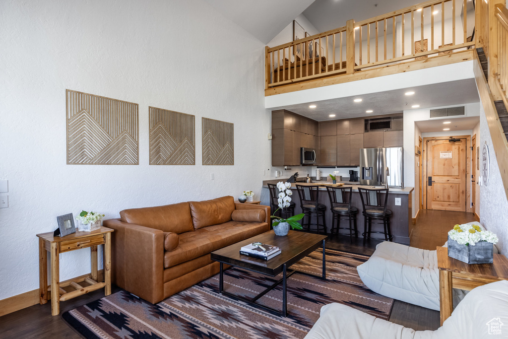Living room featuring dark wood-style floors and high vaulted ceiling