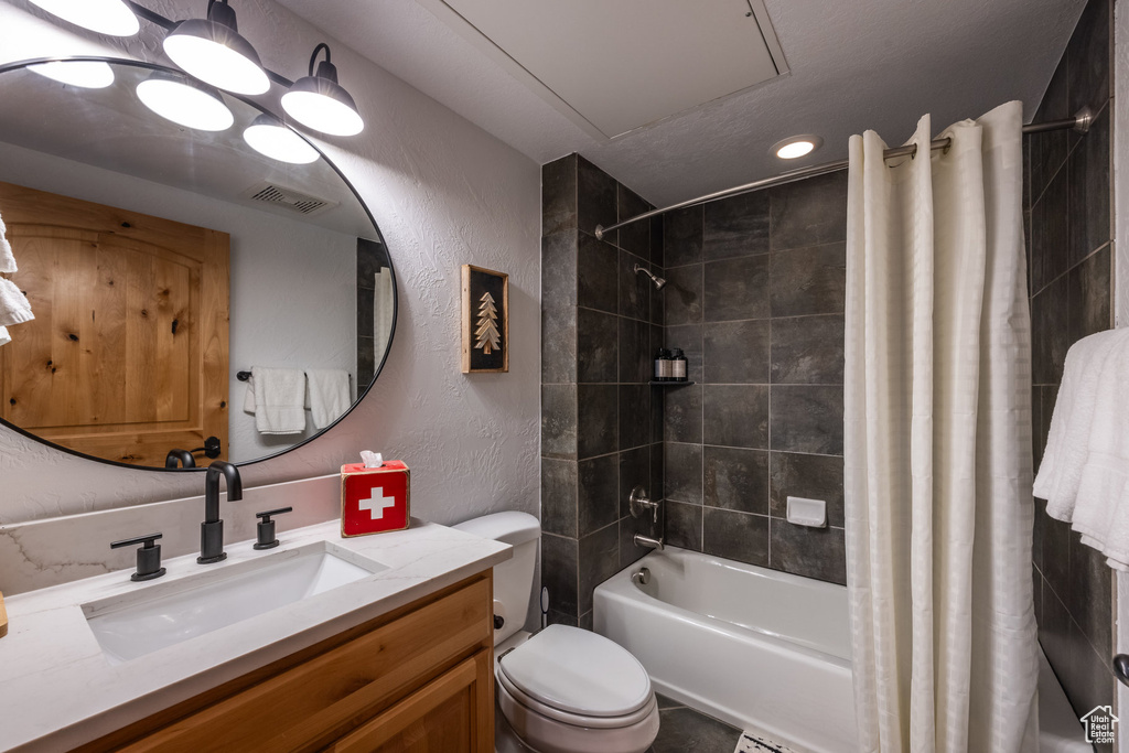 Bathroom featuring shower / tub combo with curtain, a textured wall, vanity, toilet, and recessed lighting