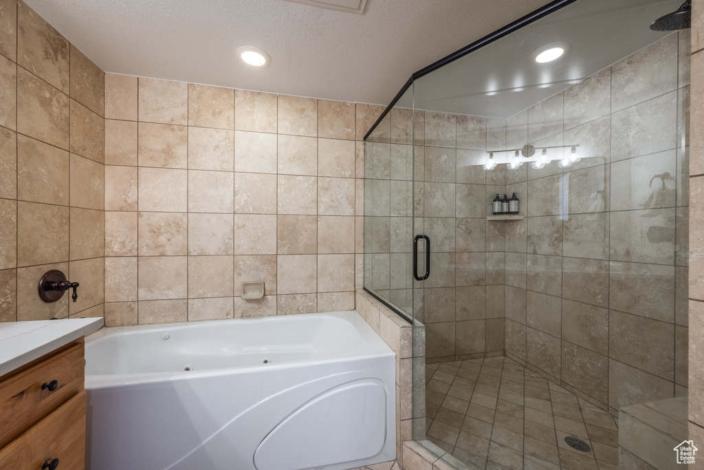 Bathroom with a shower stall, a garden tub, tile walls, vanity, and recessed lighting