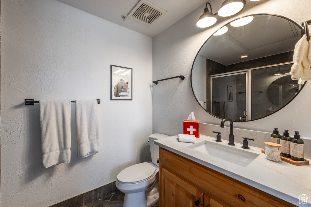 Bathroom with vanity, a stall shower, toilet, a textured wall, and baseboards